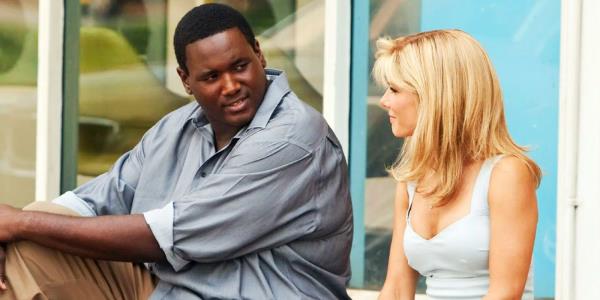 Quinton Aaron and Sandra Bullock sitting on the pavement in The Blind Side.