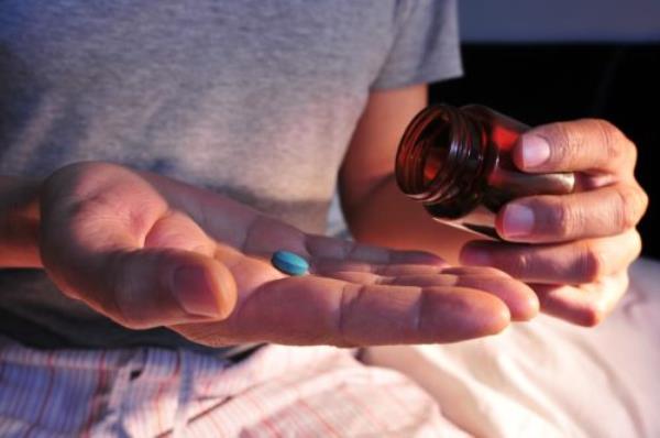 A man getting ready to take a pill of Viagra at night. 